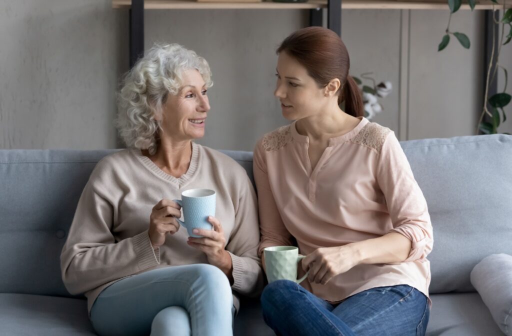 A senior woman talking to her daughter while having a cup of coffee together.