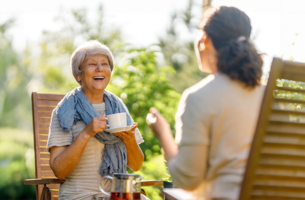 A senior woman enjoying a cup of coffee with her daughter in the backyard