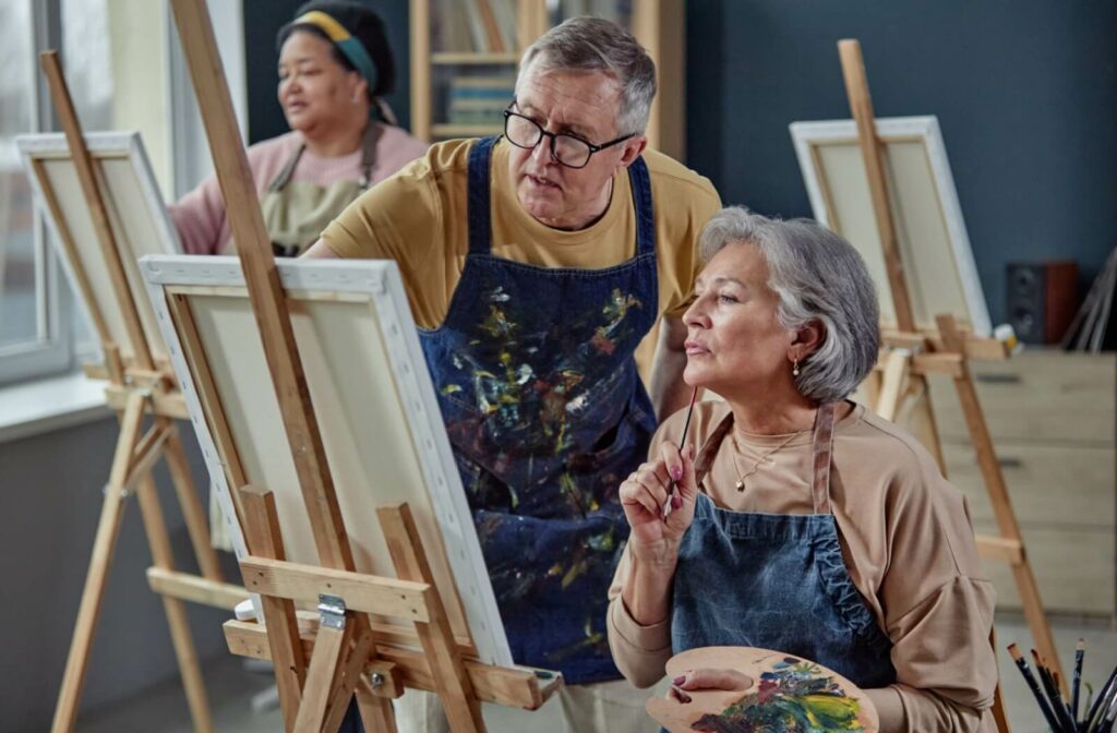 A group of seniors work on paintings together, as part of an art activity put on by their independent living community