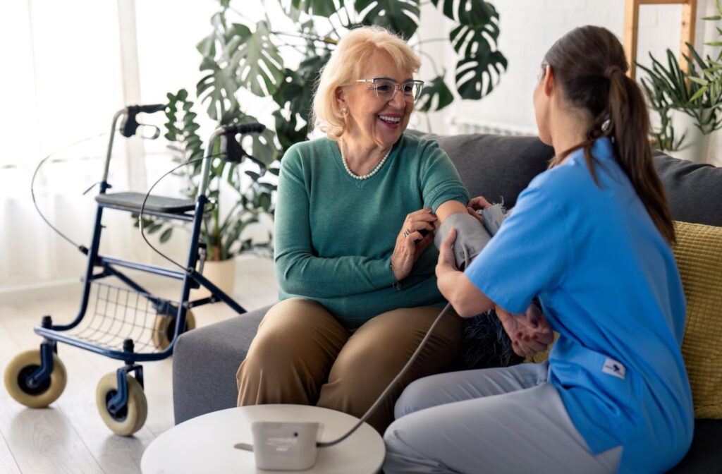 A caregiver in skilled nursing checking a smiling patient's blood pressure during a regular checkup.